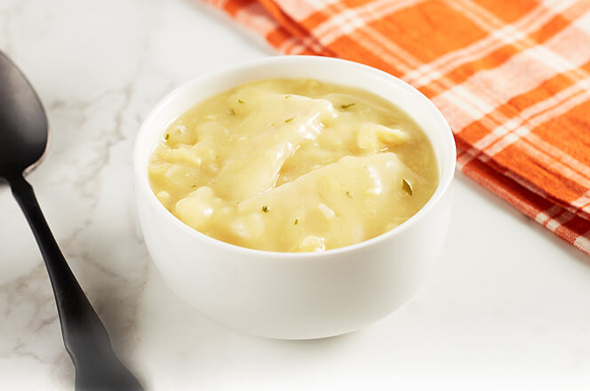 A bowl of chicken and dumplings soup with fluffy dumplings and shredded chicken.